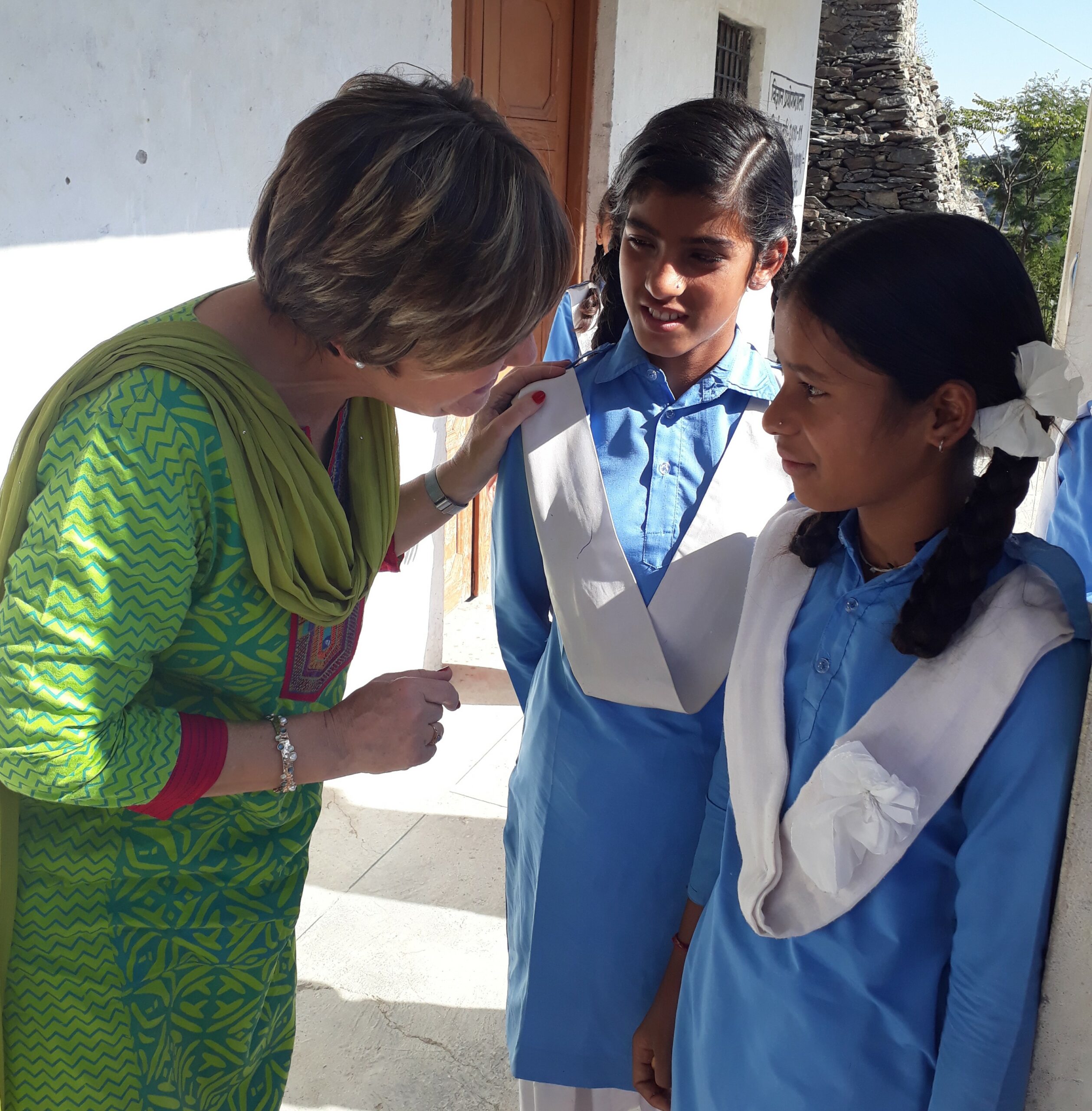 Dr. Christine Burnett talking with 2 girls in a school in India.